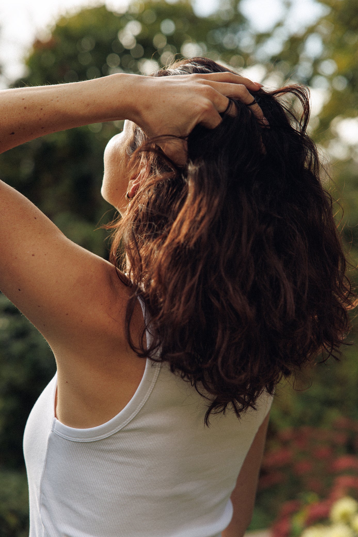 Person with long hair touching their head outdoors